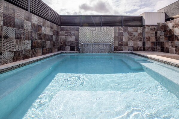 Une piscine avec un mur recouvert de carreaux et une rambarde en métal.