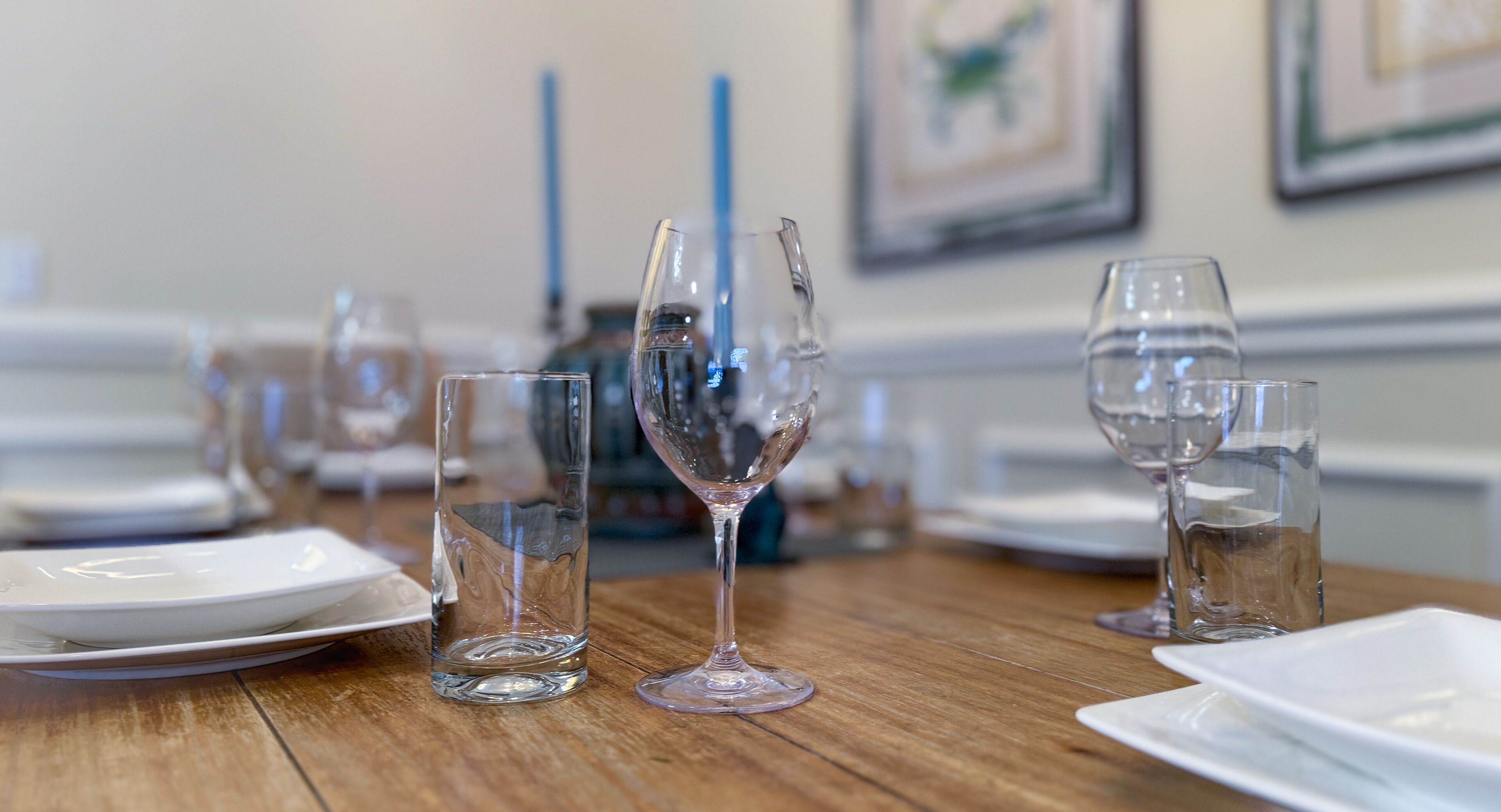 A dining table with various glassware and plates, set for a meal.