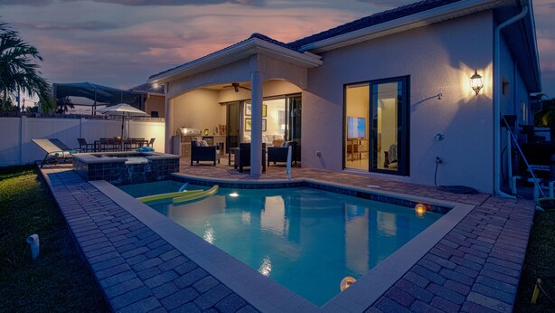 A modern house with a swimming pool, patio furniture, and a covered outdoor area.