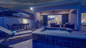 A modern outdoor pool area with lounge chairs, a hot tub, and a dining area.