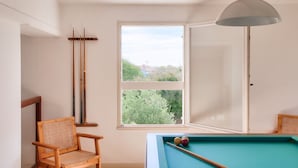 A room with a pool table, a chair, and a window with a view of greenery and buildings. - Large house for 7 400m from the beach (Sainte-Marie-de-Ré)