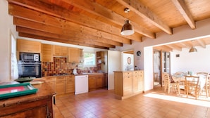 A spacious kitchen with wooden cabinets, a dishwasher, and a dining area with a table and chairs. - Large house for 7 400m from the beach (Sainte-Marie-de-Ré)
