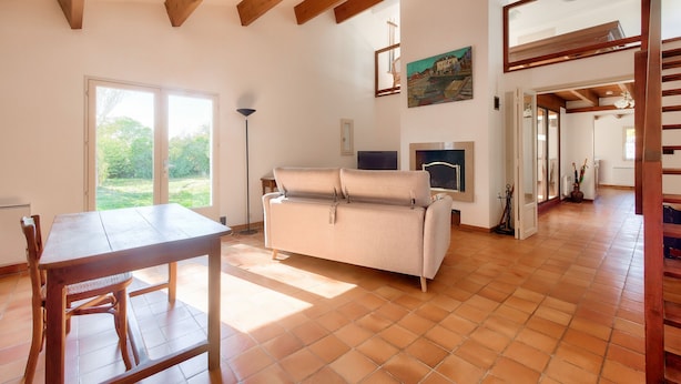 A spacious room with a wooden dining table, a sofa, and a large window. - Large house for 7 400m from the beach (Sainte-Marie-de-Ré)