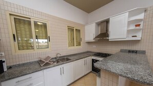 Une cuisine avec des armoires blanches, un plan de travail en granit, un évier et une cuisinière.