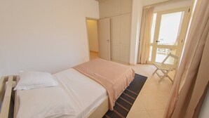 Une chambre à coucher avec un lit, une armoire et une fenêtre avec des rideaux.