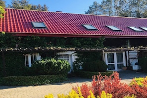 Un edificio con tejado rojo, tres tragaluces y un acceso cubierto.