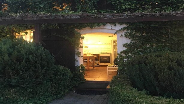 A cozy outdoor area with a wooden pergola covered in greenery, leading to a warmly lit interior space with a dining table and chairs. - Comfortable holiday home in the countryside, pool (Rozewko)