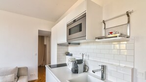 A modern kitchen with white cabinetry, a stainless steel oven, a built-in microwave, and a coffee machine. - GuestReady - lovely stay near Moulin Rouge (Paris)