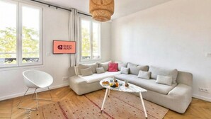 A modern living room with a sofa, a coffee table, a chair, and a 'Guest Ready' sign. - GuestReady - lovely stay near Moulin Rouge (Paris)