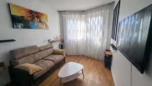 A living room with a sofa, a coffee table, a TV, and a painting on the wall.