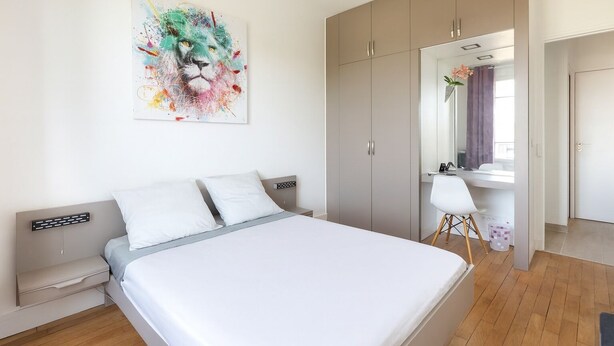 A modern bedroom with a bed, a desk, and a wardrobe.