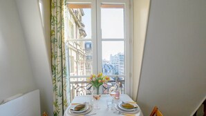 Tavolo da pranzo apparecchiato per due con vista sui palazzi attraverso una finestra.