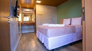A compact bedroom with a bed, bedside table, and a television mounted on the wall. - Bella Rosa Noronha (Fernando de Noronha)