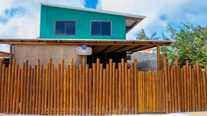 A two-story building with a teal facade and a wooden fence in front. - Bella Rosa Noronha (Fernando de Noronha)