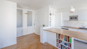 Eine moderne Küche mit weißen Schränken, einer Holzauskładung und Pendelleuchten.