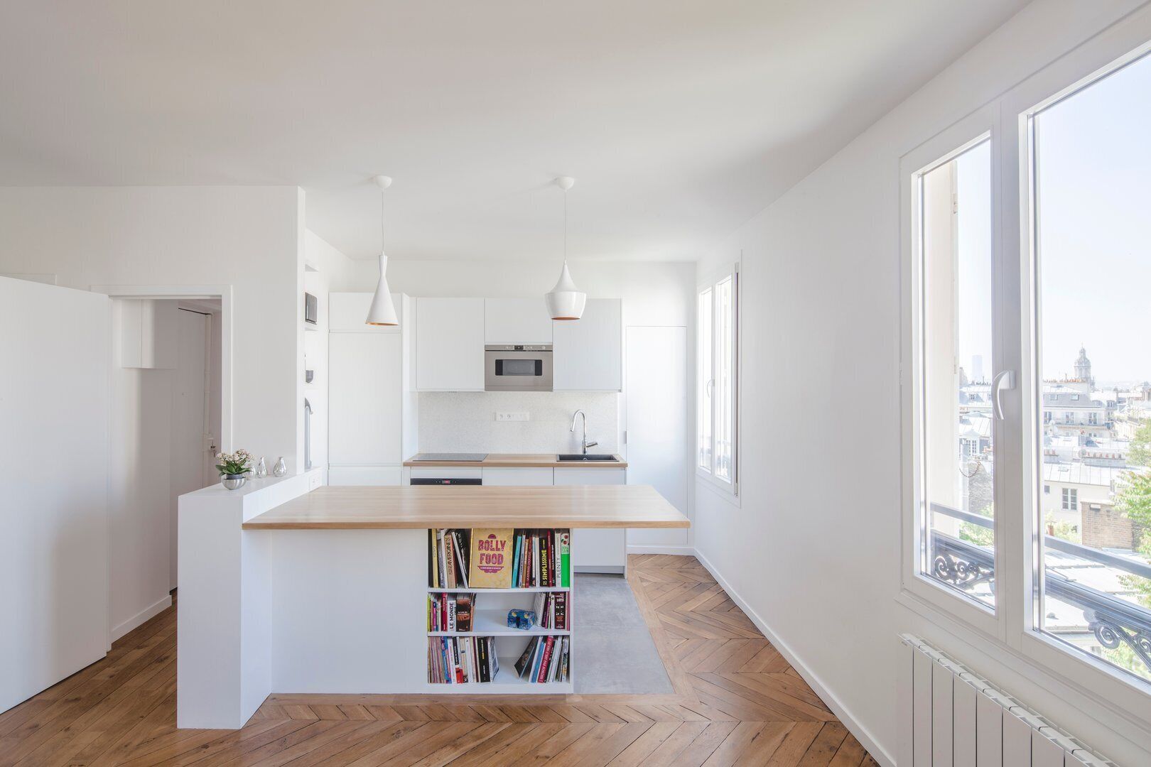 Eine moderne Küche mit weißen Schränken, einer Holz Arbeitsplatte und Pendelleuchten.