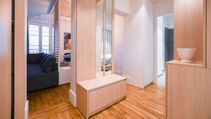 A modern, minimalist bedroom with a wooden floor, a large mirror, and a built-in bench.