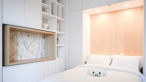 A modern bedroom with a large bed, built-in shelving, and a wooden headboard.