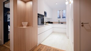 A modern kitchen with white cabinets, a built-in oven, and a wooden countertop.