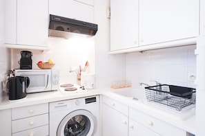 Uma cozinha moderna com micro-ondas, máquina de café e máquina de lavar.