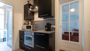 A compact kitchen with a built-in oven, microwave, and coffee maker. - GuestReady - Bright Apt in the new Quartier Latin (Paris)
