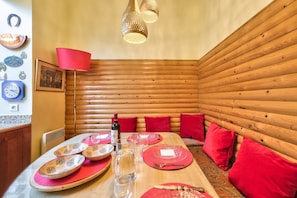 A cozy wooden cabin interior with a dining table set for four, red cushions, and a red lamp. - GuestReady - Traditional Apt near Arc de Triomphe (Paris)