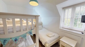 A bedroom with a bunk bed, a single bed, a bedside table, a radiator, and a window with blinds. - Stunning Coastal Cottage - Sleeping 5 in 2 Bedrooms - Pool and Beach Access Included. (Filey)