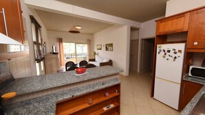 Eine Küche mit Granit Arbeitsplatten, Holzschränken, einem Kühlschrank mit Magneten und einem Essbereich mit Stühlen und Tisch.