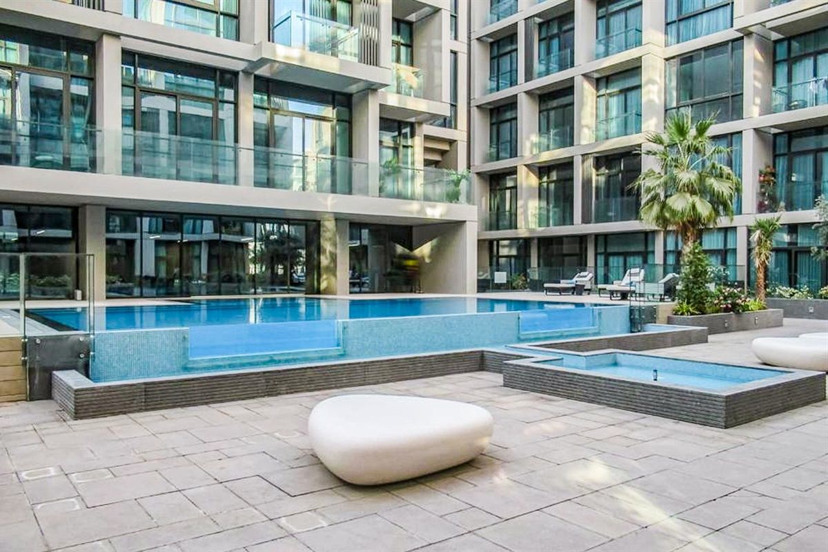Un bâtiment moderne doté d’un espace piscine sur le toit, comprenant une piscine rectangulaire et des coins salon.