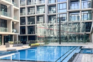 A modern building with a glass facade, a rooftop pool, and outdoor seating areas. - Luxurious 1BR Suite Signature Livings in Dubai (Dubai)