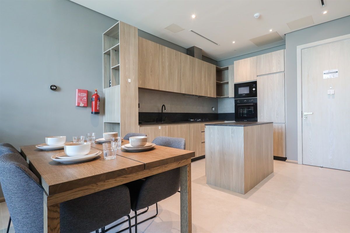 A modern kitchen with wooden cabinets, a central island, and a dining area with a table set for four.