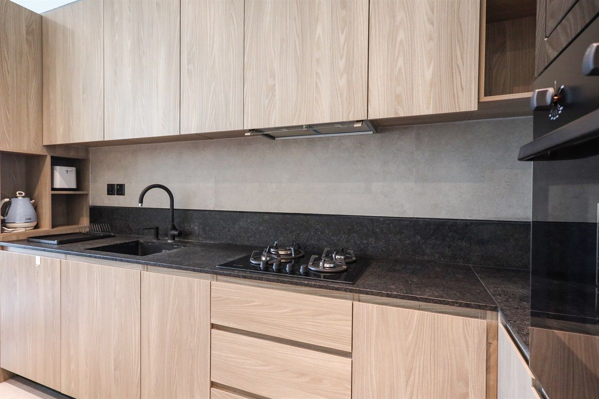 Eine moderne Küche mit Holzschränken, einer schwarzen Arbeitsplatte und einem Gasherd.