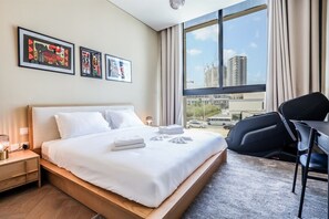 A hotel room with a bed, a desk, and a view of the cityscape. - Luxurious 1BR Suite Signature Livings in Dubai (Dubai)