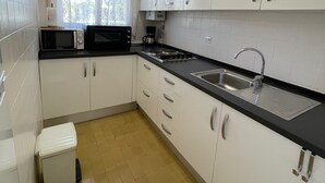 A compact kitchen with white cabinets, a black countertop, a microwave, a coffee maker, and a sink. - SAONA VILLAS (VN CARL) : Villa, private swiming pool, wifi, 4 people (Tres Calas)