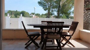 A patio with a table and chairs, a white fence, and trees in the background. - SAONA VILLAS (VN CARL) : Villa, private swiming pool, wifi, 4 people (Tres Calas)