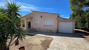 A single-story house with a stone-paved driveway, a front door, and a garage. - SAONA VILLAS (VN CARL) : Villa, private swiming pool, wifi, 4 people (Tres Calas)
