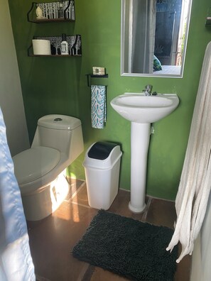 Uma casa de banho com sanita, lavatório e lixeira.