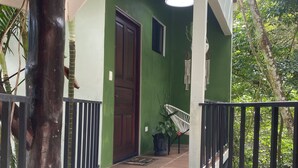 A green-walled entrance with a wooden door, a metal railing, and a potted plant. - Jungle luxury on a budget,, brand new space (Puerto Carrillo)