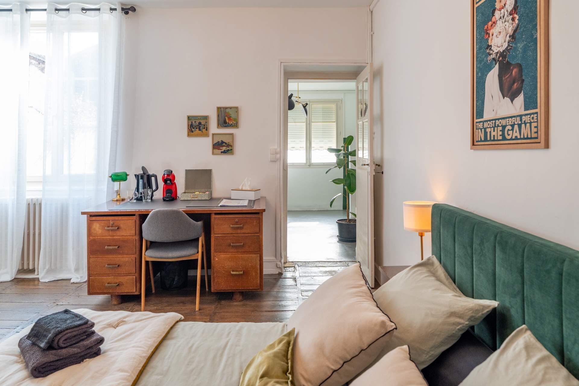 Un dormitorio acogedor con una cama, un escritorio con una silla, una lámpara y una planta en maceta.