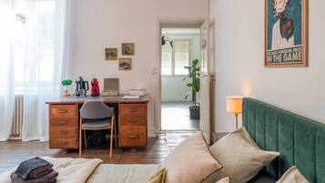 Un dormitorio acogedor con una cama, un escritorio con una silla, una lámpara y una planta en maceta.