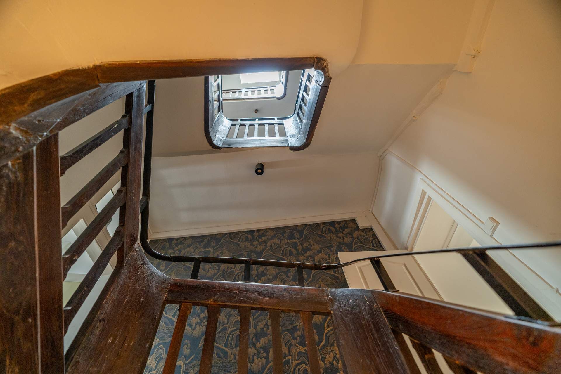 A wooden staircase with a metal handrail leading to a landing.