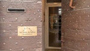 Una puerta de madera con un letrero que dice 'Les Suites de Bellac' y una ventana que ofrece vistas a un edificio.