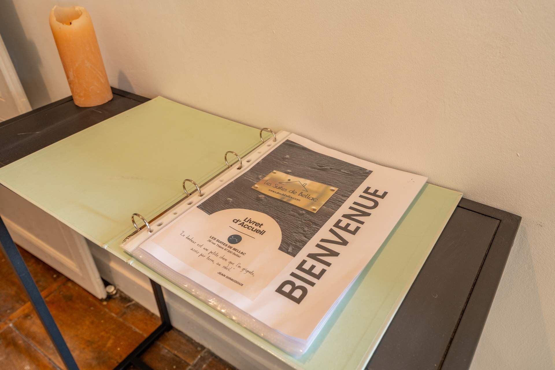 Un folleto de bienvenida sobre una mesa con una vela y un archivador.