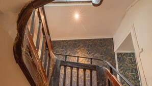 Una escalera de madera de diseño tradicional que conduce a una habitación con papel tapiz estampado.