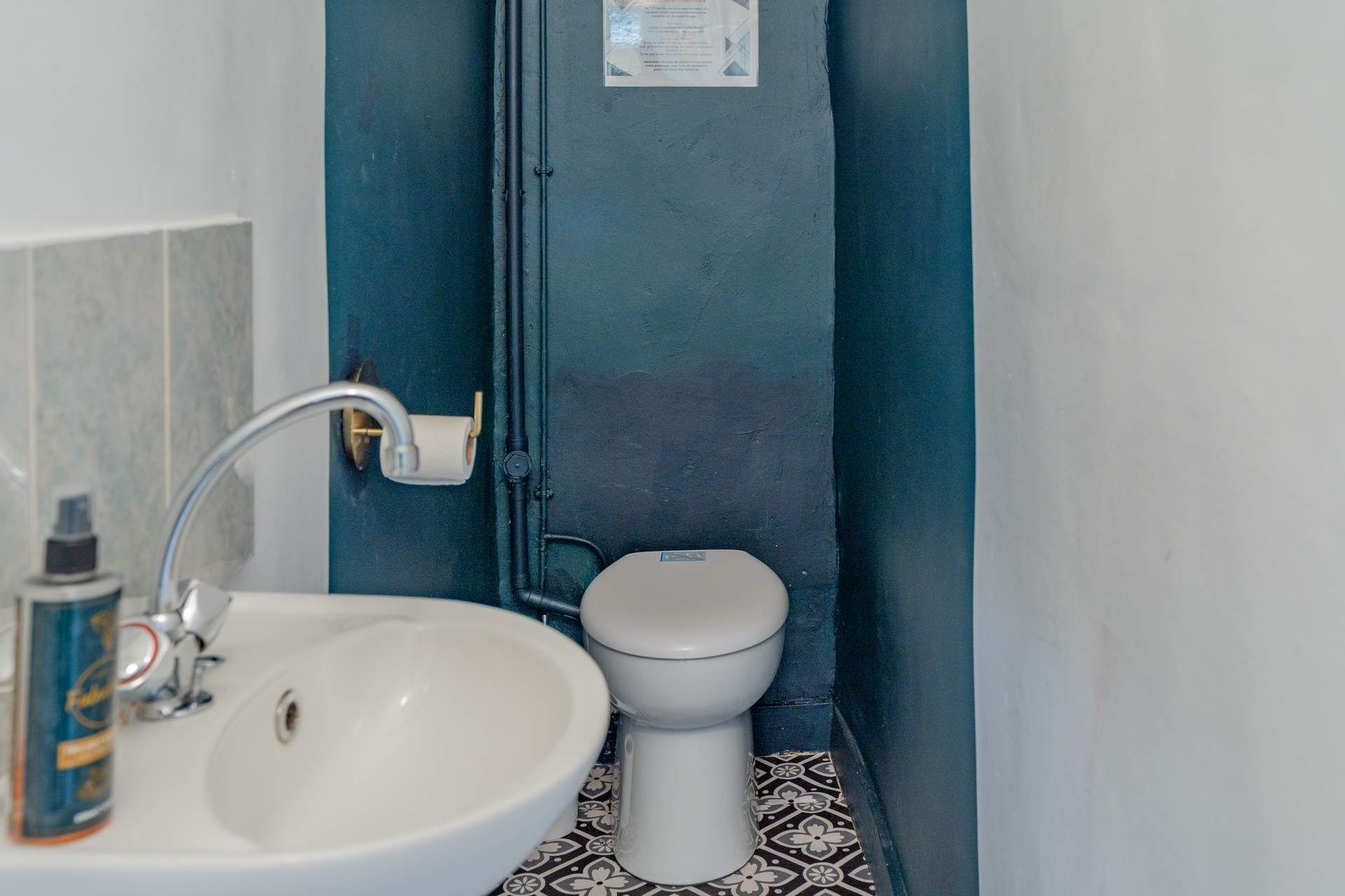 A bathroom with a white sink, a toilet, and a blue door.