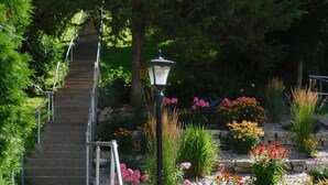 Una escalera de concreto con barandas de metal que lleva a un jardín con diversas plantas y flores.