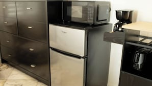 A compact kitchen with a stainless steel refrigerator, a microwave, and a coffee maker.