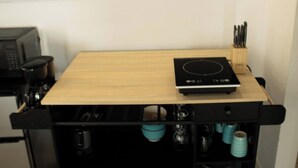 A kitchen counter with a microwave, a coffee maker, and a black induction cooktop.