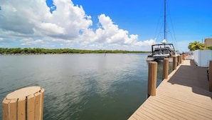 A wooden dock extending into calm waters with a clear sky and a distant shoreline.
