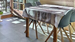 Eine moderne Küche mit Geschirrspüler, Holzschränken und einem Essbereich mit Tisch und Stühlen.